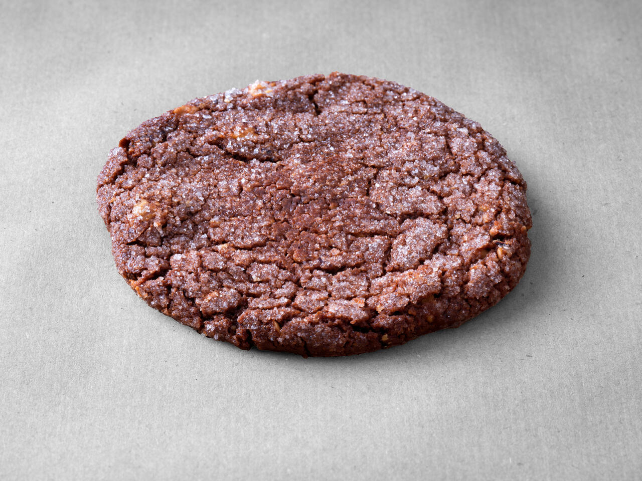 Cookie chocolat noisettes posé sur un fond gris