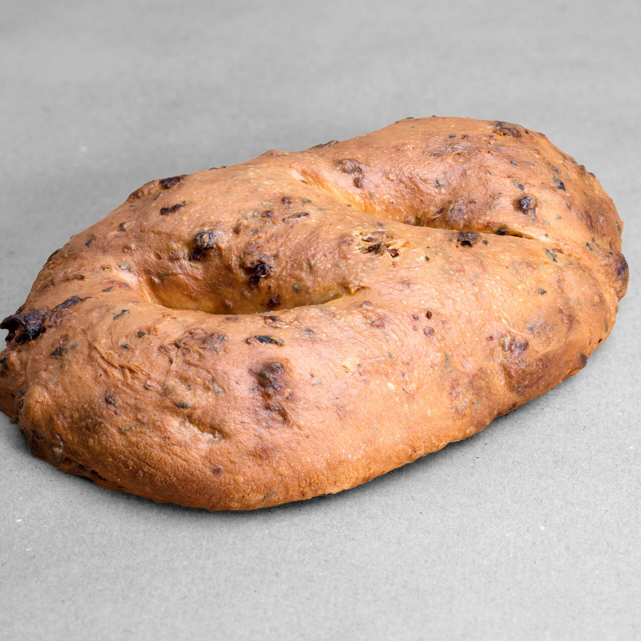 Fougasse tomates séchées, ail et basilic posées sur un fond gris