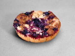Tartelette saveur noisettes et myrtilles posée sur un fond gris