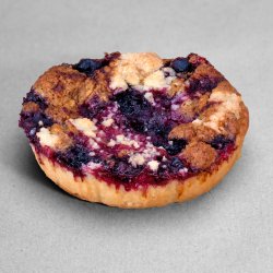 Tartelette saveur noisettes et myrtilles posée sur un fond gris