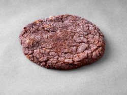 Cookie chocolat noisettes posé sur un fond gris