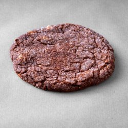 Cookie chocolat noisettes posé sur un fond gris